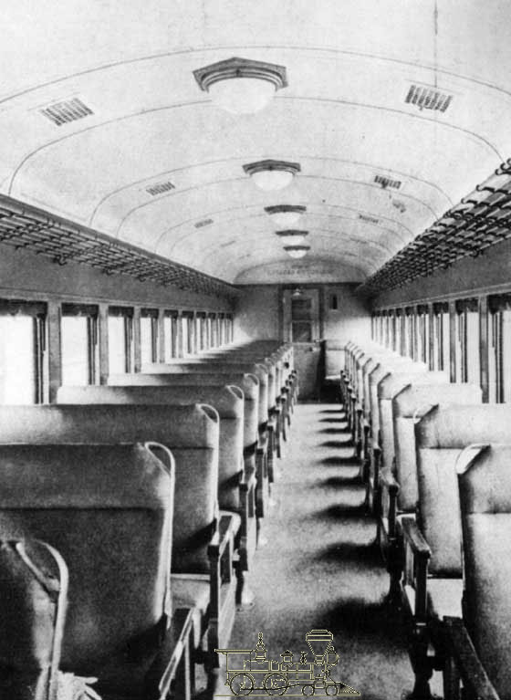 Interior de um vagão de Primeira classe com assentos duplos não-repartidos (à esquerda)