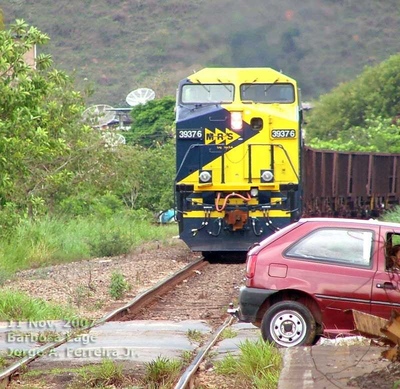 Automóvel cruzando os trilhos diante da locomotiva AC38EMi nº 3937 MRS na passagem de nível em Barbosa-Lage