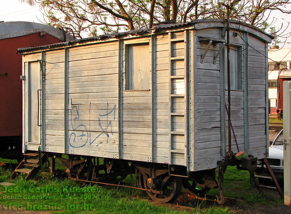 Pequeno vagão de dois eixos (quatro rodas) em exposição na estação de Bento Gonçalves, junto ao trem turístico da Ferrovia do Vinho