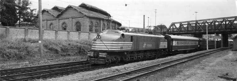 Passagem de um trem puxado pela locomotiva V8 embaixo de um viaduto ferroviário