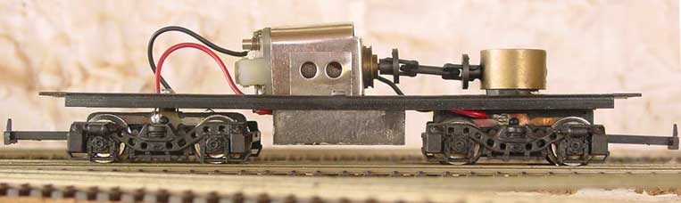 Vista de perfil do Ferreomodelo de locomotiva Frateschi sem a casca, mostrando o motor Oxford da fase 2, cardã de transmissão, truque redutor, truque de contato e fiação,  de perfil
