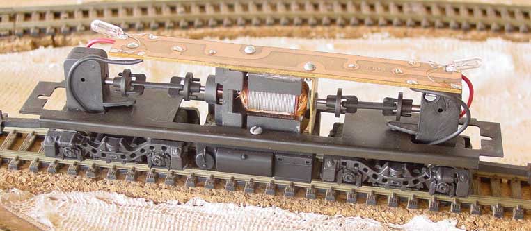 Ferreomodelo de locomotiva Frateschi sem a casca, mostrando o motor, cardã de transmissão, truques redutores,  fiação, circuito impresso e micro-lâmpadas, do alto