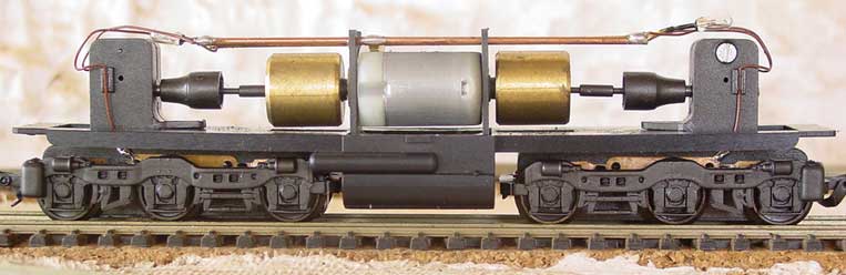 Ferreomodelo de locomotiva Frateschi sem a casca, mostrando o motor, cardã de transmissão, truques redutores, volantes de inércia (flywheel), fiação e micro-lâmpadas, de perfil